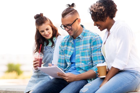 students with notebook and takeaway drinks