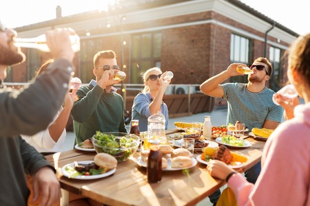 happy friends with drinks or bbq party on rooftop