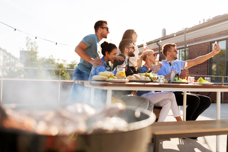 happy friends taking selfie at rooftop partyの写真素材