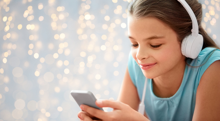 children, technology and people concept - close up of happy girl with smartphone and headphones...