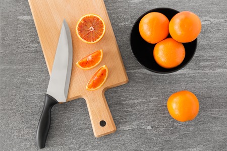 close up of oranges and knife on cutting board