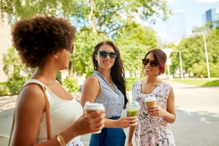 leisure, people and friendship concept - happy women or friends with takeaway drinks talking summer...