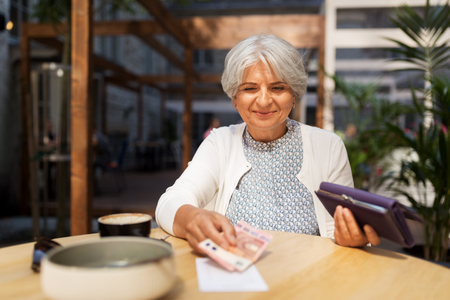 senior woman with money paying bill at cafeの写真素材