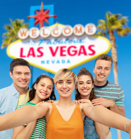happy friends taking selfie over las vegas signの写真素材