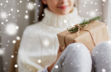 girl with christmas gift sitting on sill at homeの写真素材