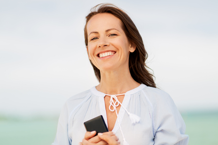 happy woman with smartphone on summer beachの写真素材