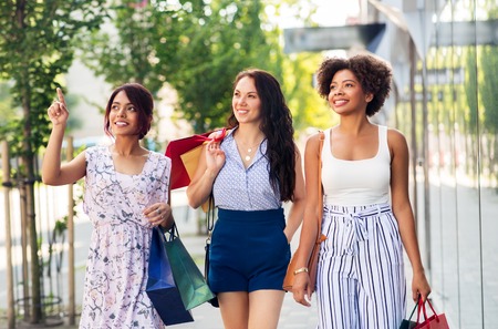happy women with shopping bags walking in cityの写真素材