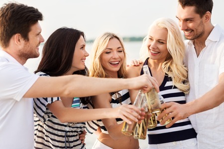 happy friends drinking non alcoholic beer on beachの写真素材