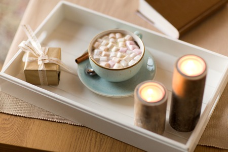 hot chocolate, christmas gift and candles on table