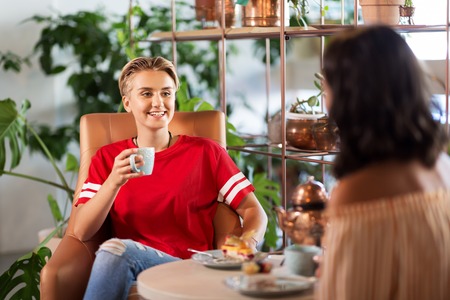 female friends drinking coffee and talking at cafe