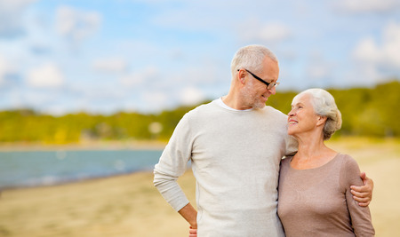 happy senior couple hugging over beach backgroundの写真素材