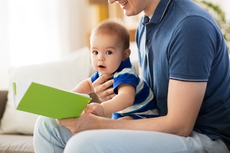 baby boy and father with book at homeの写真素材