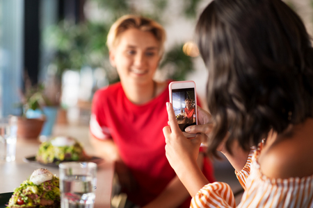 women having lunch and photographing at cafeの写真素材
