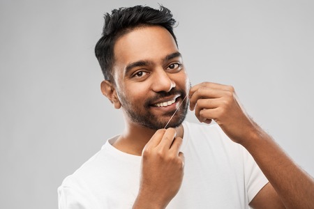 indian man with dental floss cleaning teethの写真素材
