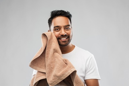 smiling indian man with towel over grey backgroundの写真素材