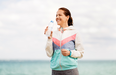 woman drinking water after exercising at seasideの写真素材