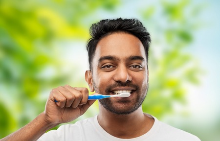 indian man cleaning teeth over natural backgroundの写真素材