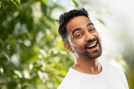 laughing indian man over green natural background