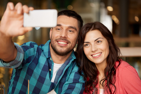 couple taking selfie by smartphone at restaurantの写真素材