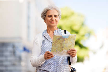 senior woman or tourist with map on city streetの写真素材