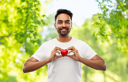 indian man with red heart over natural backgroundの写真素材