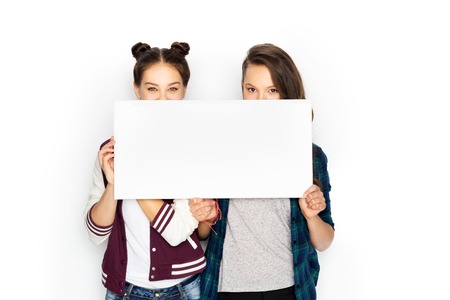happy teenage girls holding blank white boardの写真素材