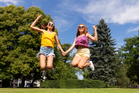 happy teenage girls jumping at summer parkの写真素材