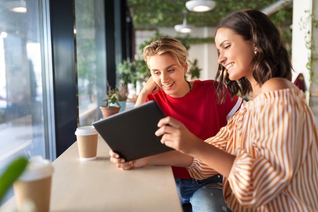 female friends with tablet pc and coffee at cafeの写真素材
