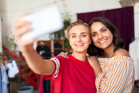 female friends taking selfie at clothing storeの写真素材