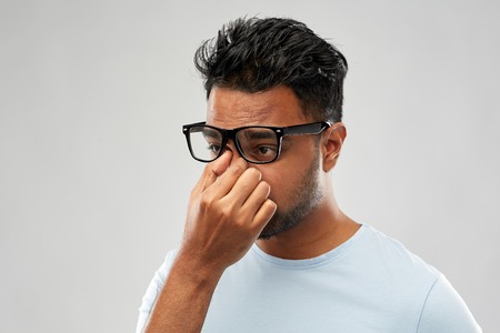 tired indian man in glasses rubbing nose bridge