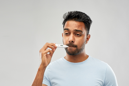 man measuring oral temperature by thermometerの写真素材
