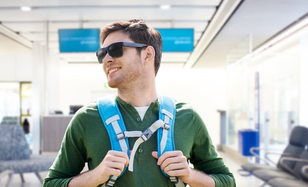 smiling man with backpack over airport terminalの写真素材