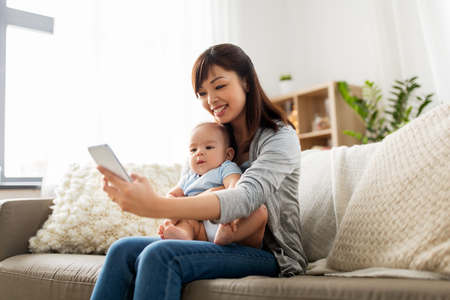 happy mother with baby son taking selfie at homeの写真素材