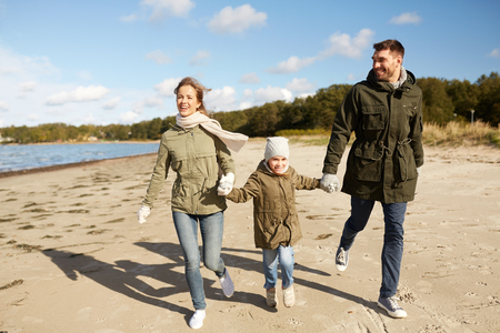 happy family running along autumn beachの写真素材