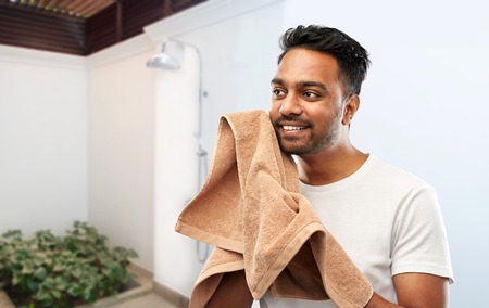 smiling indian man with bath towel over shower