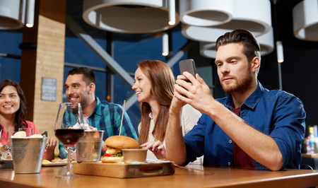 man messaging on smartphone at restaurantの写真素材