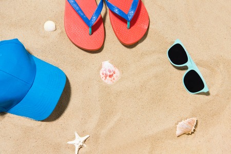 cap, flip flops, shades and on shells beach sandの写真素材