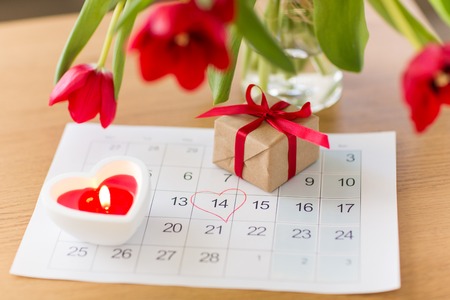 gift box, calendar sheet and flowers on tableの写真素材
