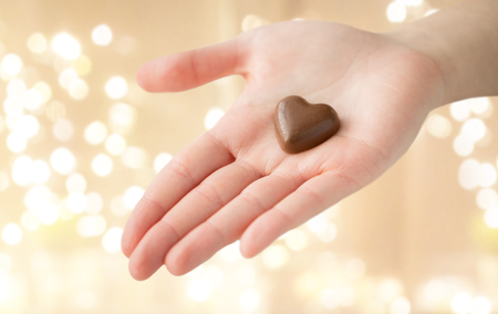 close up of hand with heart shaped chocolate candyの写真素材