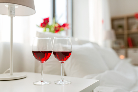 two glasses of wine on bedroom nightstand at homeの写真素材