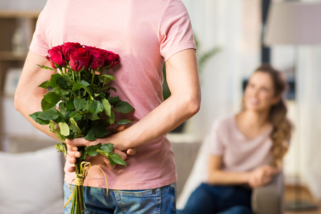 woman and man with bunch of roses behind his backの写真素材