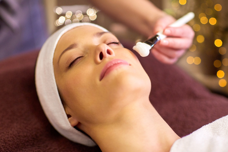 beautician applying facial mask to woman at spaの写真素材