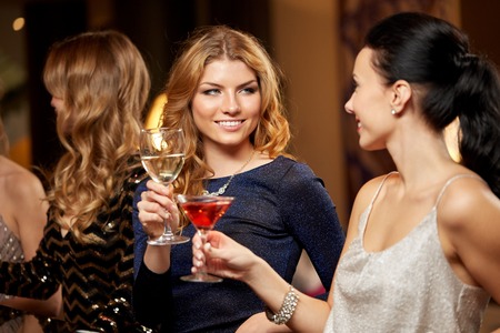 Happy women clinking glasses at night clubの写真素材