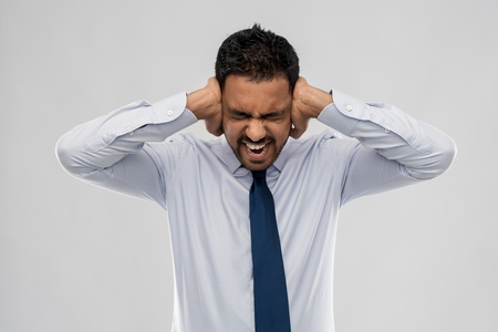 screaming businessman covering ears with handsの写真素材