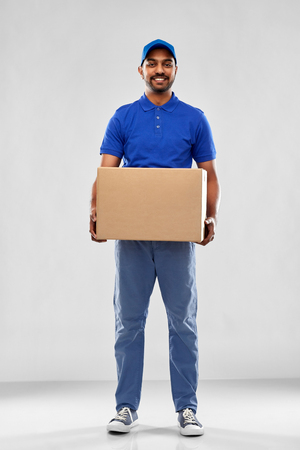 happy indian delivery man with parcel box in blueの写真素材