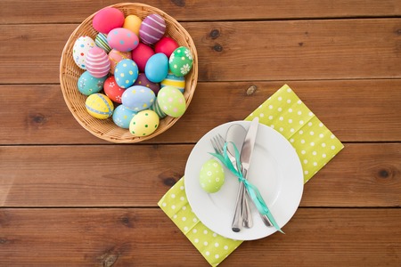 easter eggs in basket, plates, cutlery and flowers