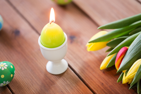 candle in shape of easter egg and tulip flowersの写真素材