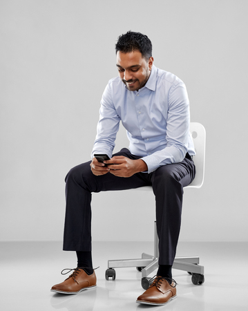 smiling indian businessman sitting on office chairの写真素材