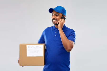 indian delivery man with smartphone and parcel boxの写真素材