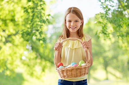 happy girl with colored eggs in wicker basketの写真素材